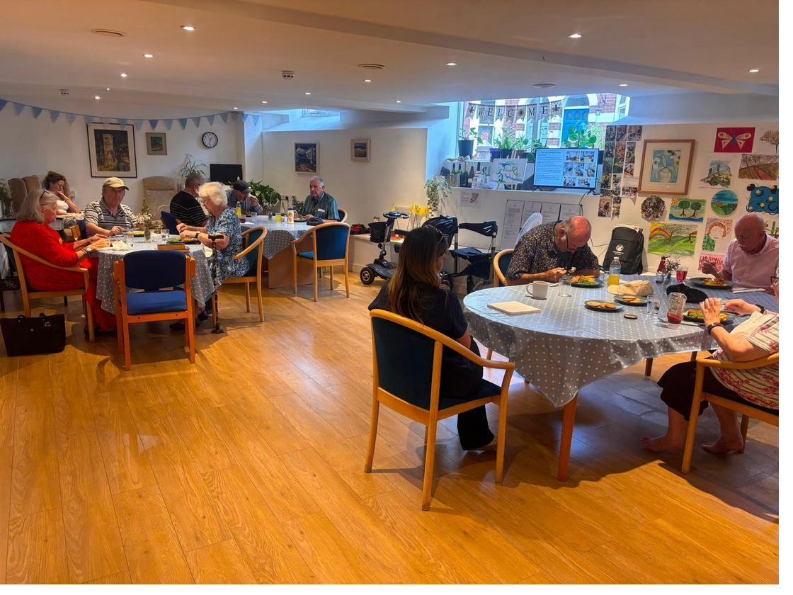 Lunch being served at tables around the main room, with guests' artwork covering the far wall